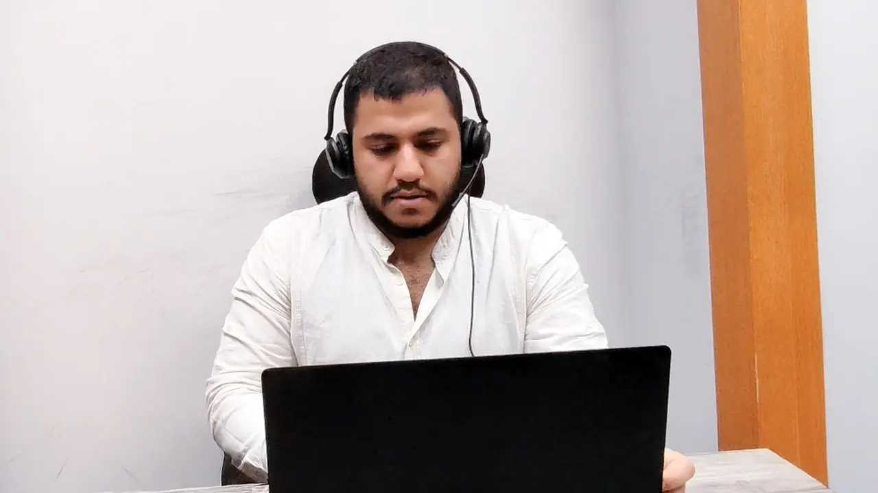 A human agent wearing a headset works at a laptop in a plain, bright office — multilingual customer support case study