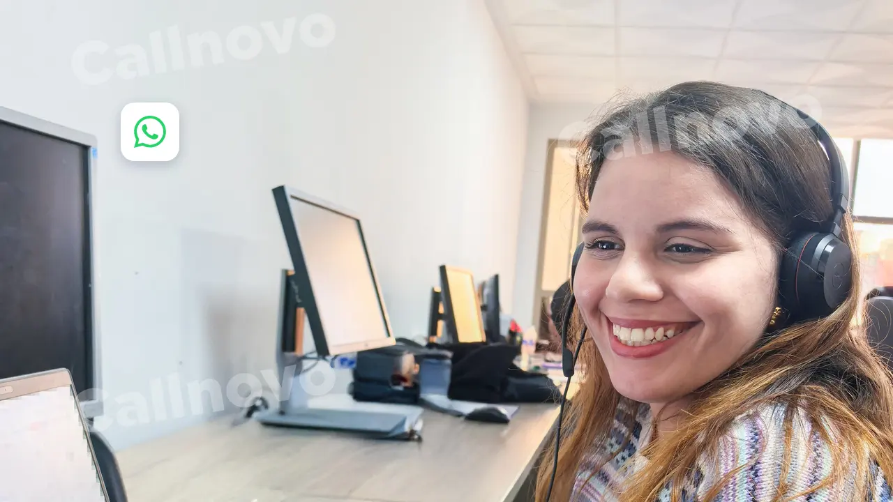 Una agente con auriculares sonríe frente a su puesto, con el icono de WhatsApp en la esquina: chatbot de WhatsApp y paso a un agente humano