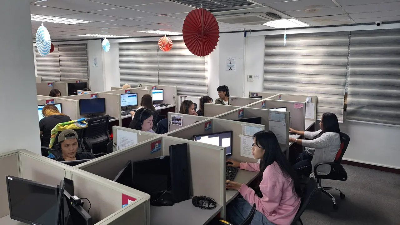 Agents wearing headsets work at rows of desks on a contact center floor — ecommerce call center outsourcing
