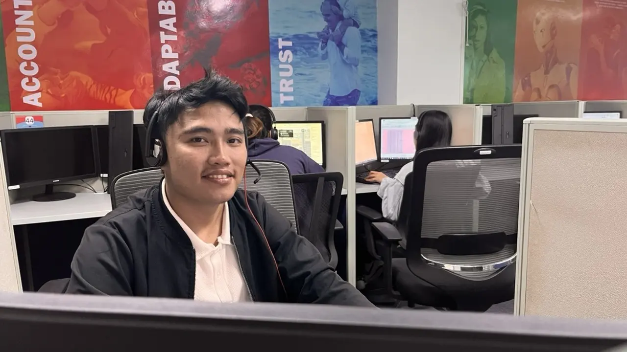 Ein Mitarbeiter mit Headset sitzt an seinem Platz im Großraumbüro eines Callcenters – KI-Telefonassistent und Übergabe an Menschen