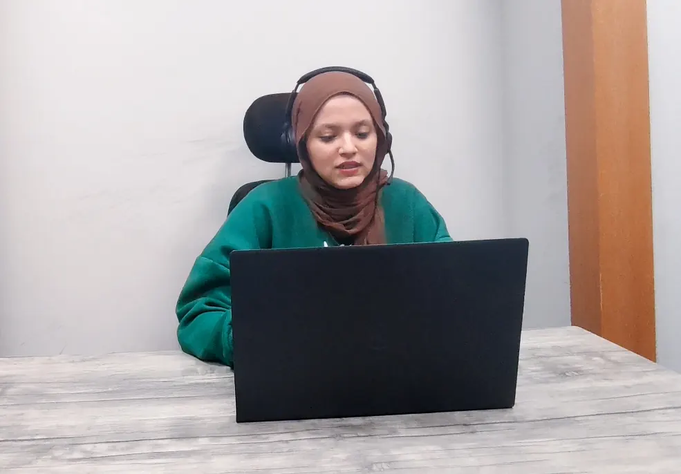 A Callnovo.ai human agent wearing a headset works on a laptop at a plain desk
