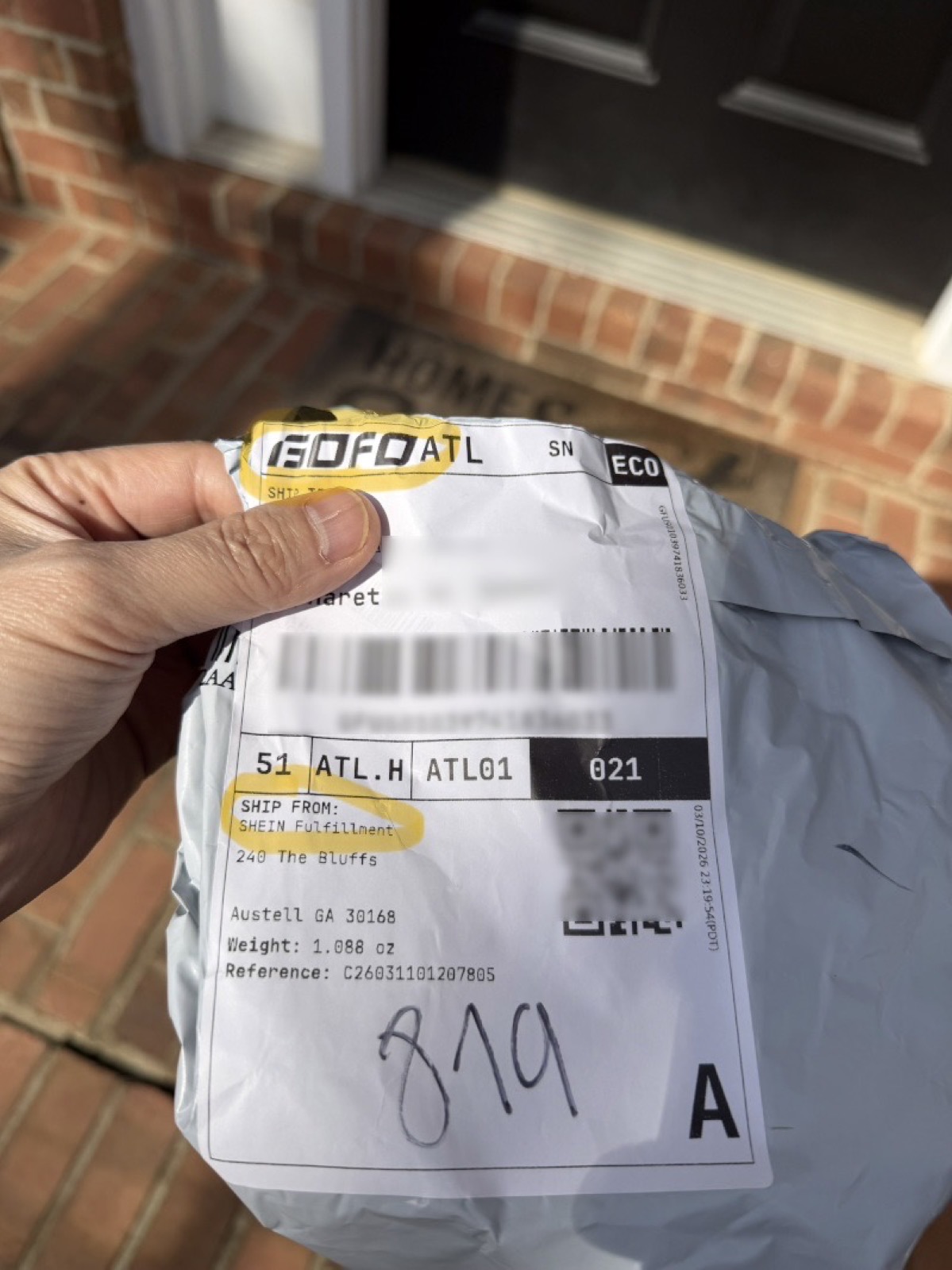 A Shein package delivered by GOFO logistics — the shipping label shows "GOFO ATL" and "SHIP FROM: SHEIN Fulfillment" on a poly mailer held at a front door