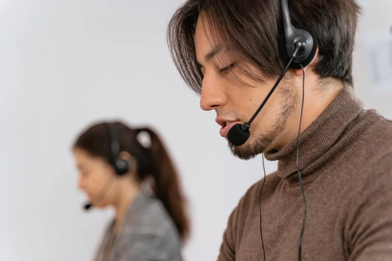 A support agent mid-call on a headset, a colleague answering beside him — the live team behind the AI