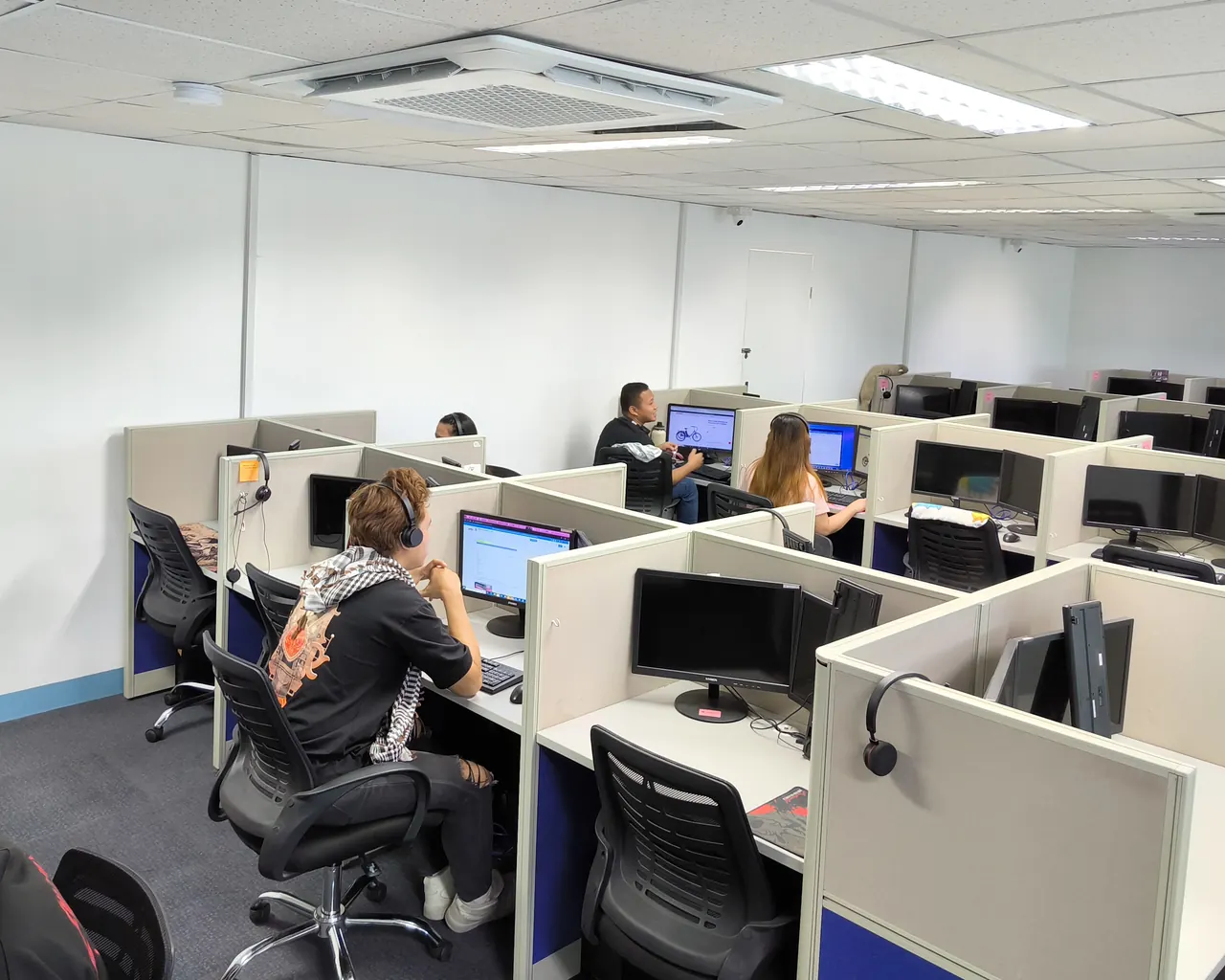 Agents wearing headsets work at rows of partitioned desks on a Callnovo contact center floor