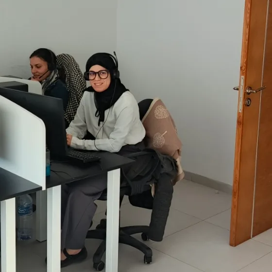 Two headset-wearing colleagues seated at computer workstations.