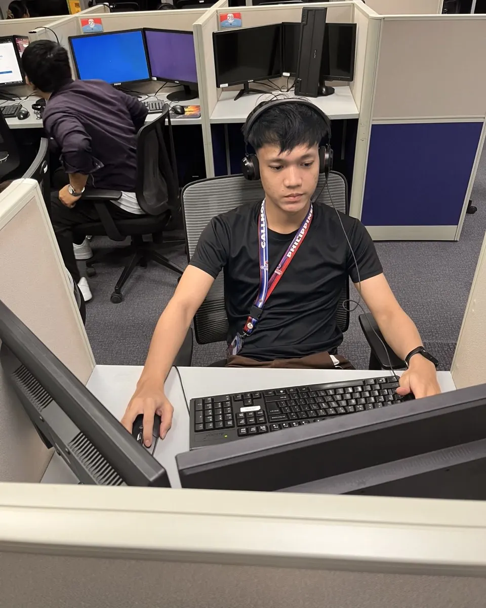 A Callnovo support agent wearing a headset works at his keyboard in a partitioned workstation